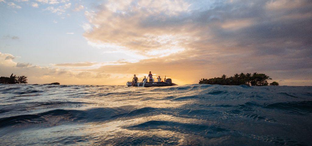 Group of people on a boat in the Caribbean Sea at sunset, exploring unique coastal destinations and marine life.