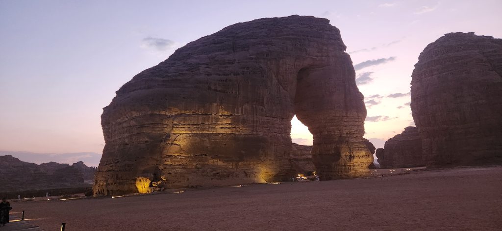 Elephant Rock at sunset, showcasing its iconic sandstone arch illuminated against the evening sky in AlUla, Saudi Arabia.