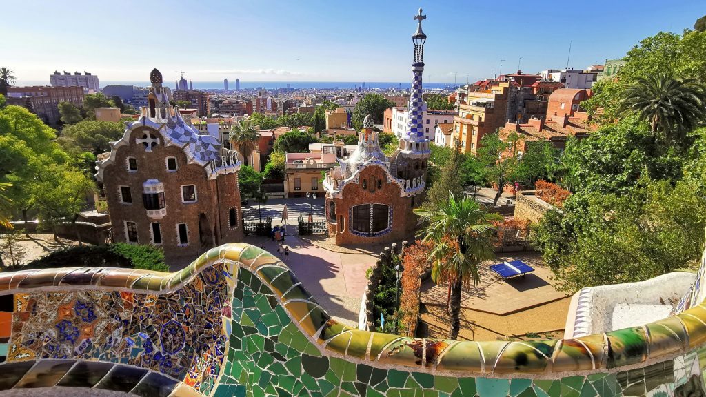 Barcelona's Park Güell featuring colorful mosaic architecture, panoramic city view, and lush greenery, highlighting unique travel experiences.