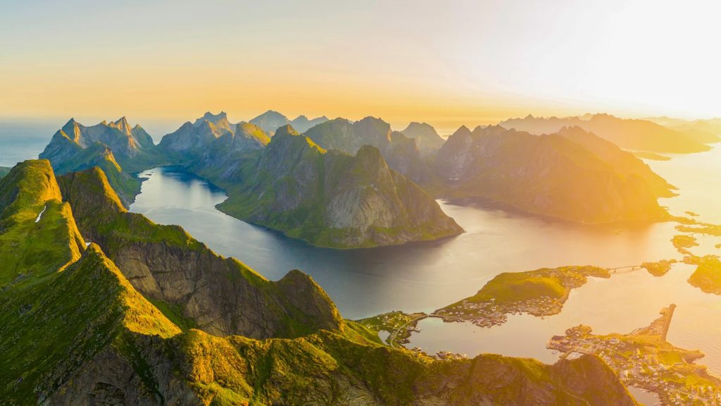 Stunning aerial view of Svalbard's rugged mountains and serene waters at sunset, highlighting the natural beauty of the Arctic region.